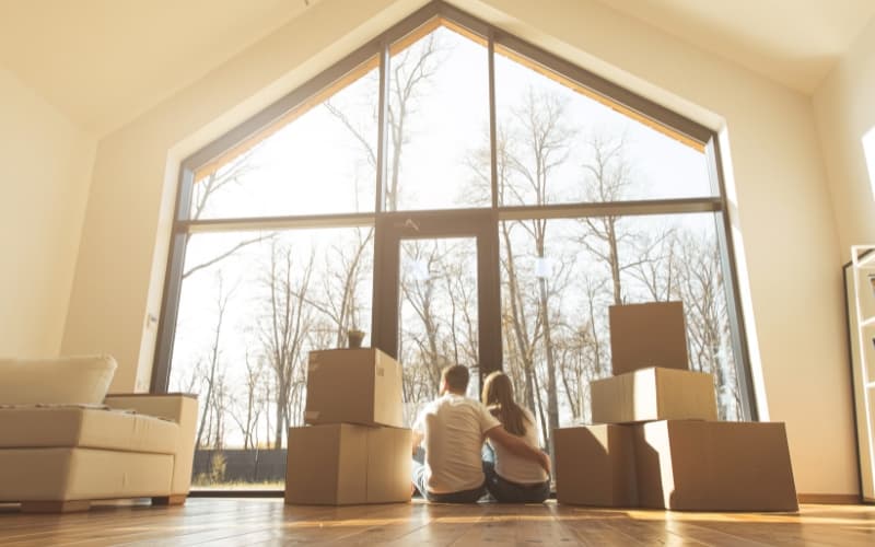 couple sitting in front of a large window after moving into a new house